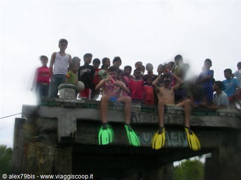 Kids standing on a concrete wall, two boys wearing yellow and green fins