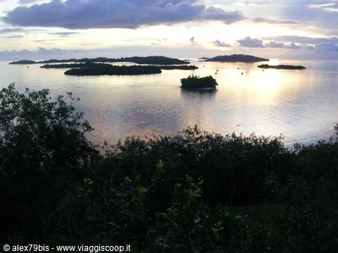Scattered islands on calm sea under golden cloudy sky at dusk