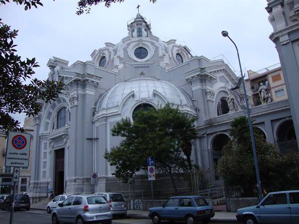 Church with large grey dome and curved facade, cars parked along the street
