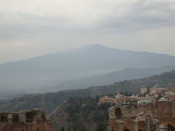 Ancient theatre of Taormina, brick ruins and columns, hazy Mount Etna