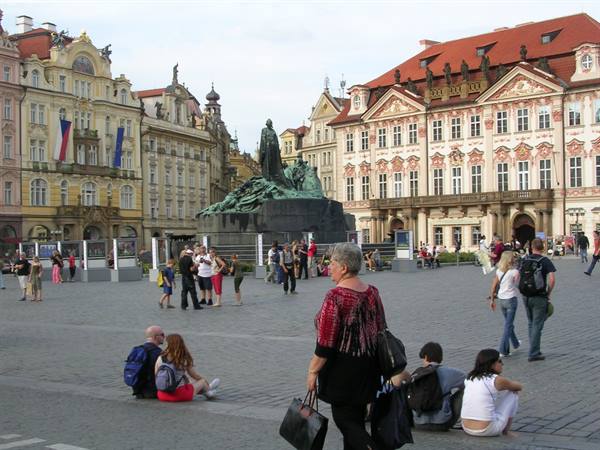 Tourists sitting on the square in front of the Jan Hus monument in Prague