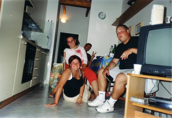 Four friends laughing in a bright tiled kitchen next to the TV