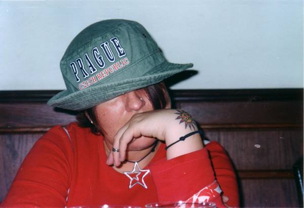 Girl in green Prague bucket hat and red sweater, sitting at a table