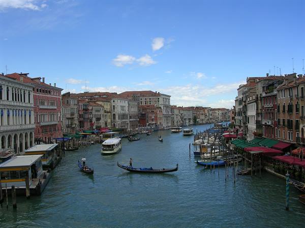 Gondolas and vaporetto on Venice's Grand Canal, colorful palaces under blue sky