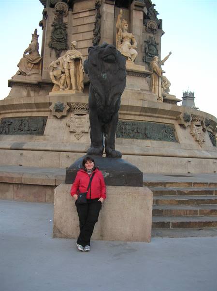 Woman in red jacket beneath the bronze lion of the Columbus Monument