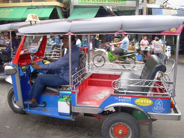 Blue and red tuk-tuk with driver at the wheel near the flower market