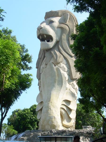 The white Merlion statue in Singapore, framed by green trees and blue sky