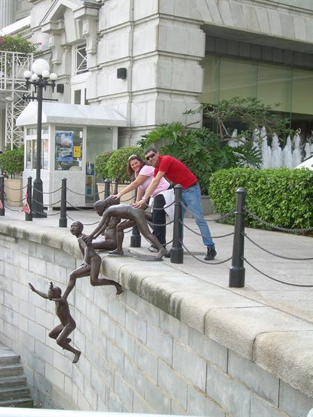 Couple posing with bronze sculptures of children jumping into the river, Singapore