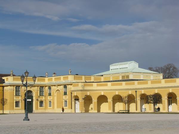 Yellow façade of Schönbrunn with arches under blue sky