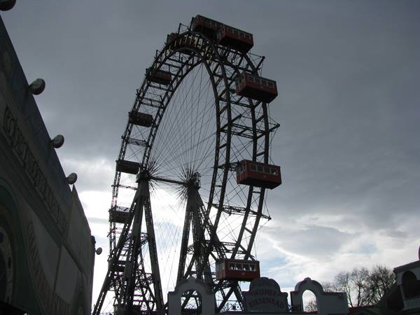 The metal Riesenrad ferris wheel with red cabins against cloudy sky in the Prater