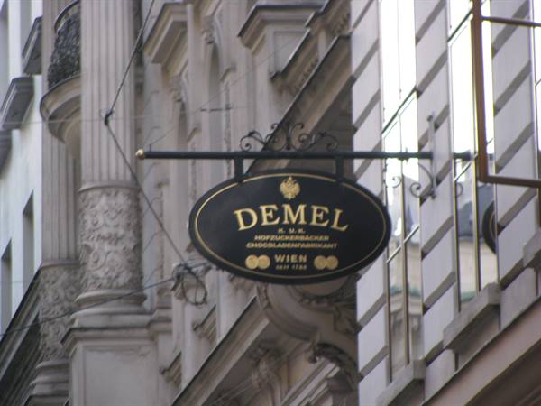 Black and gold oval sign of Demel café hanging on a Viennese building