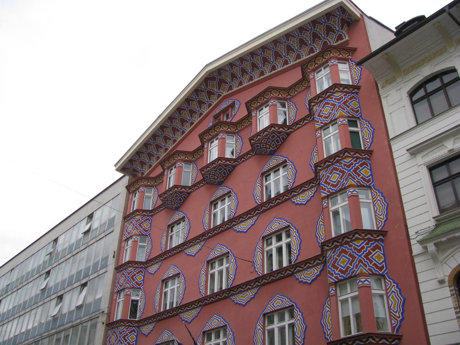Pink facade painted with colorful geometric folk patterns, Ljubljana