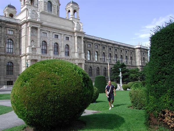 Man walks among rounded shrubs in front of Vienna's Naturhistorisches Museum