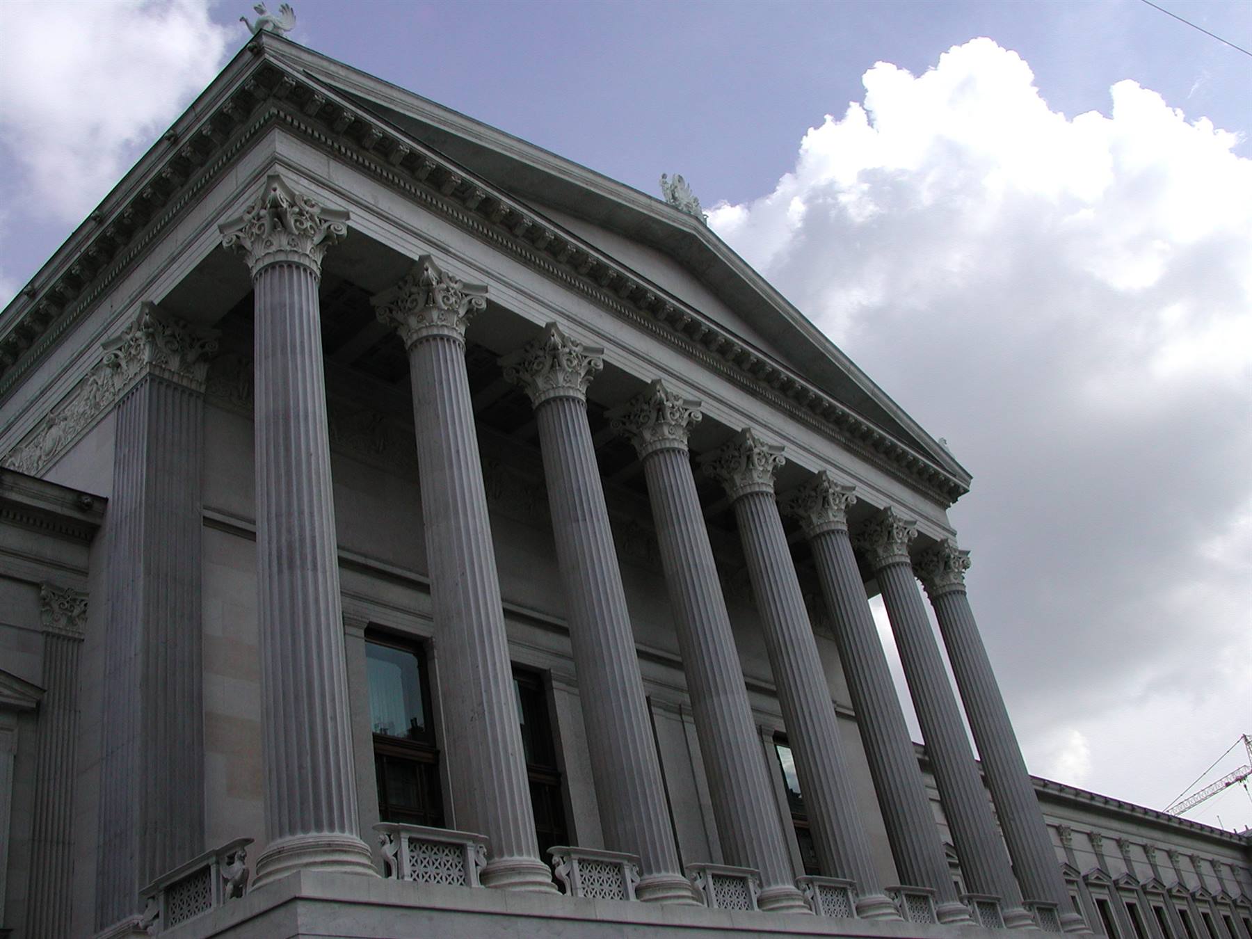 Neoclassical facade with towering Corinthian stone columns beneath cloudy sky