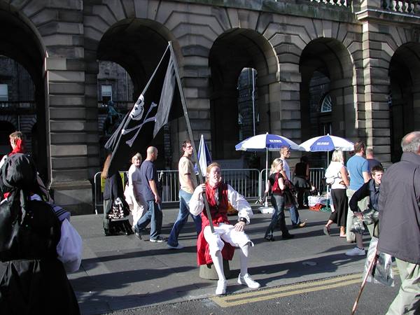 Performer in red costume with pirate flag before Edinburgh's stone arches