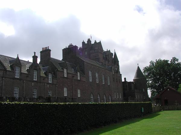 Glamis Castle, grey stone walls amid lawn, hedge and cloudy sky