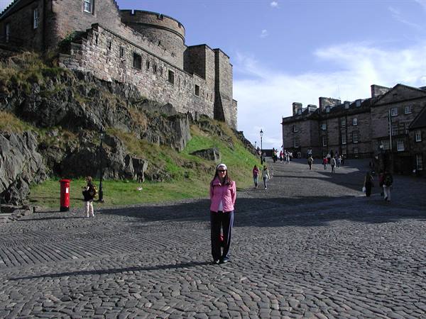 Woman in pink jacket on cobblestones in front of Edinburgh Castle