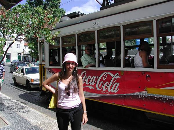 Girl in pink hat beside Coca-Cola tram 552 in Lisbon