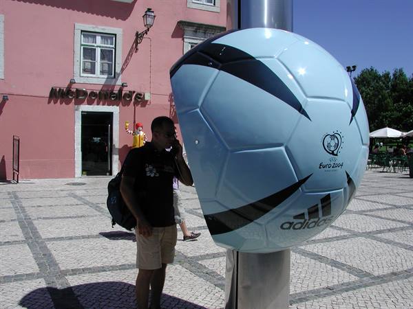Tourist calling inside a giant Adidas Euro 2004 football phone booth