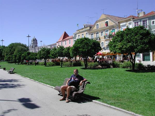 Man sitting on a wooden bench in a park with colorful houses in Lisbon