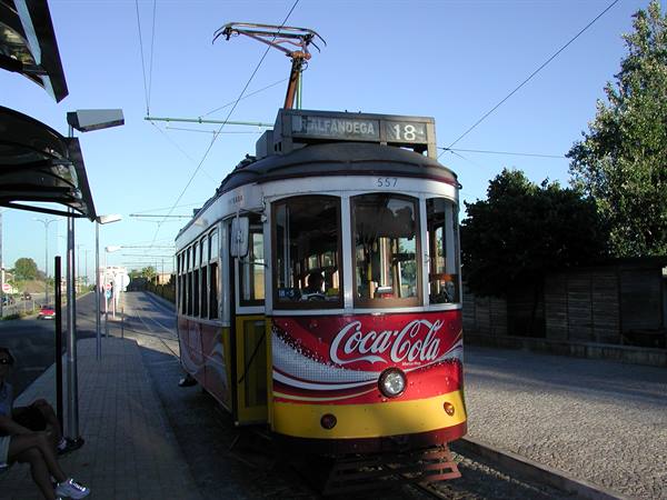 Yellow and red tram number 18 to Ajuda stopped at the stop, Coca-Cola ad