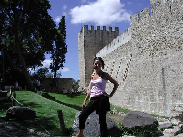 Woman posing beneath the crenellated walls of São Jorge Castle, Lisbon
