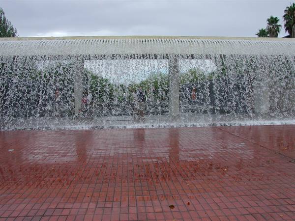 Water curtain of a fountain flowing onto red brick pavement