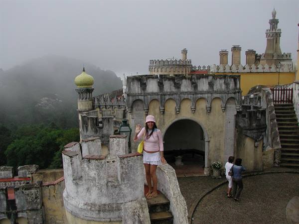 Tourist waves from a tower of Pena Palace in Sintra, fog all around