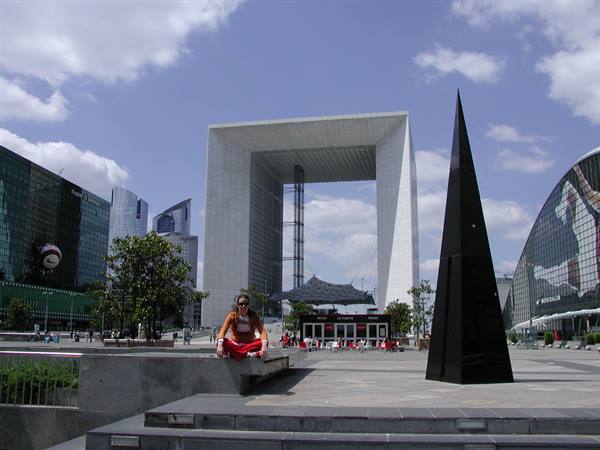 Woman sitting on steps in front of the Grande Arche de la Défense, Paris