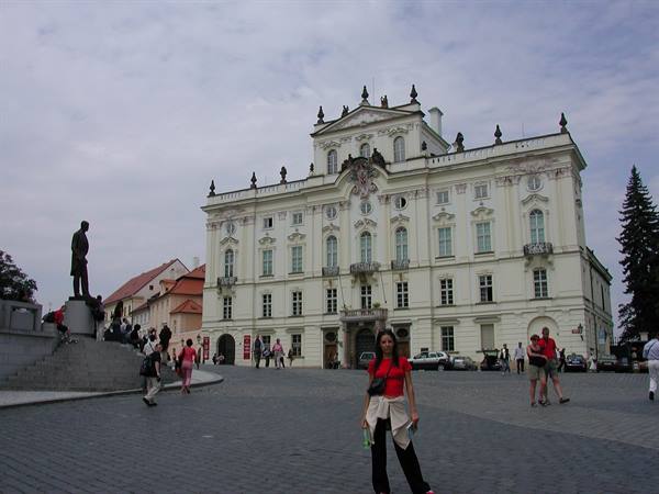 Tourist on Hradčany Square in front of the white baroque palace and Masaryk statue
