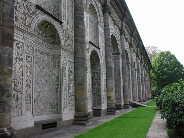 Stone facade with carved reliefs and arches beside green lawn, Dresden Zwinger