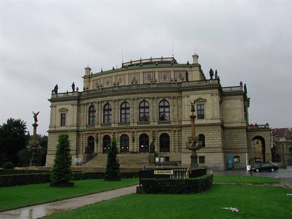 The Rudolfinum in Prague, neo-Renaissance facade under grey sky, wet lawn