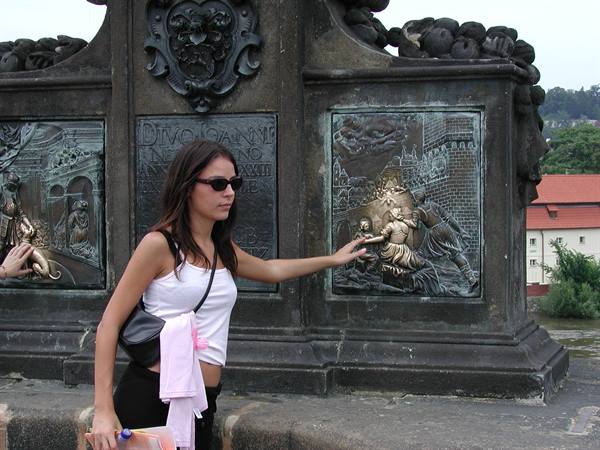 Woman touches the bronze relief of Saint John of Nepomuk on Charles Bridge