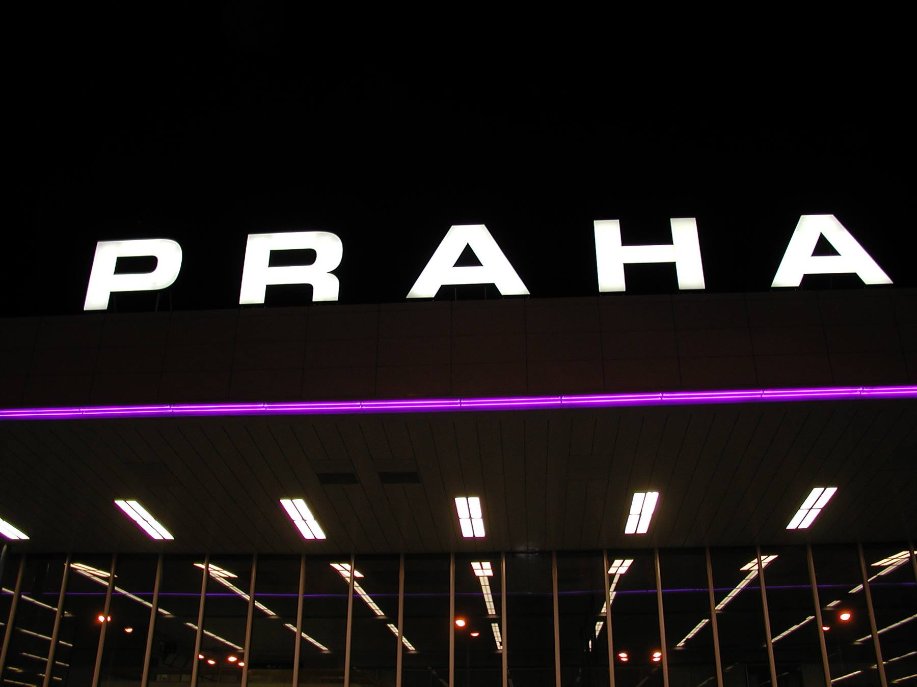 Illuminated PRAHA sign at night on building with purple lighting