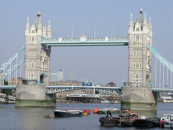 Tower Bridge in London, stone towers over the Thames with moored boats