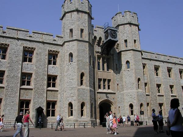 Tourists walk past the stone turrets of the Tower of London