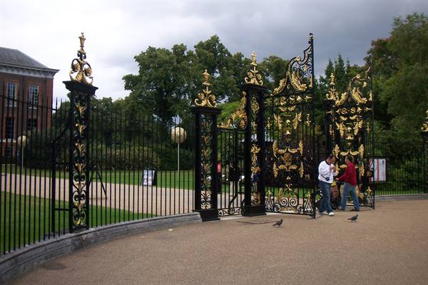 Tourists by the gilded wrought-iron gates of Kensington Palace, overcast sky