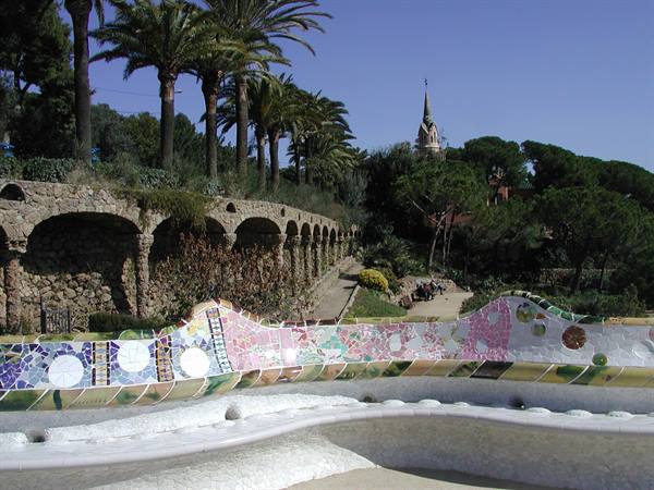 Colorful mosaic bench and stone viaduct at Park Güell, Barcelona