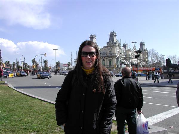 Girl in sunglasses in front of the Port de Barcelona building