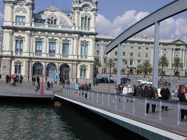 Tourists walking on the wooden Rambla de Mar footbridge by the Customs building, Barcelona