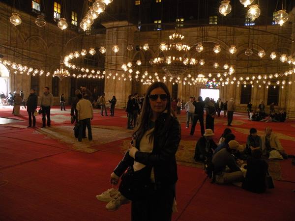 Tourist inside Cairo's Mosque of Muhammad Ali, hanging lamps and red carpets