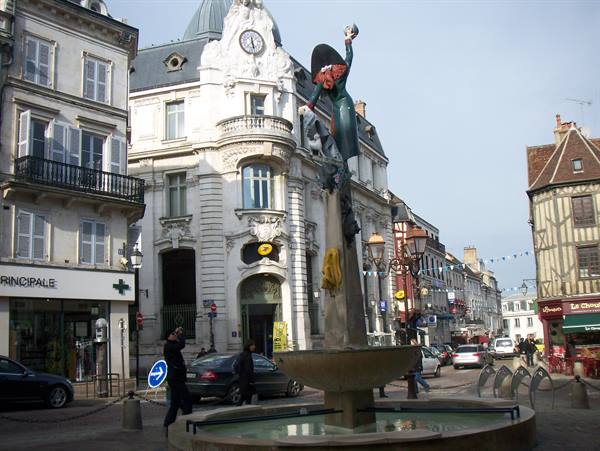 Fountain with statue in front of historic half-timbered buildings, Troyes
