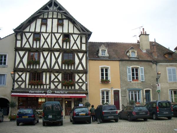 Half-timbered butcher shop house, parked cars on cobbled square
