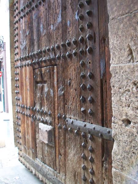 Old studded wooden gate with iron hinges, next to stone walls