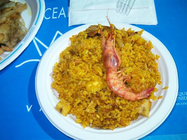 Plate of paella with whole prawn on top of yellow rice