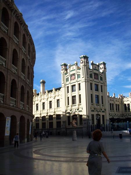 Valencia bullring and modernist Norte station, woman walking under blue sky