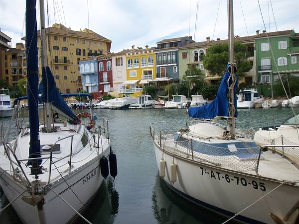 Sailboats moored at Port Saplaya marina in front of colorful houses