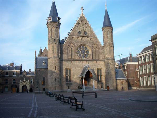 Ridderzaal in The Hague: brick Gothic facade with towers, empty chairs on the square
