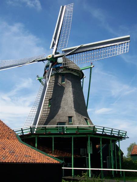 Wooden windmill with lattice sails, red-tiled roof, under a blue sky