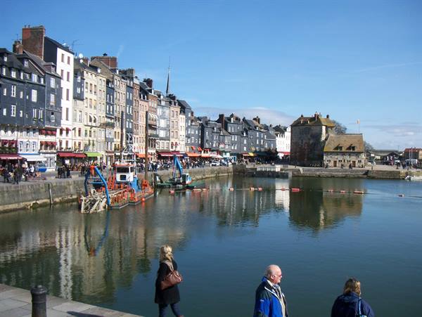 Tourists stroll along Honfleur's Vieux Bassin, waterfront houses reflected in the water